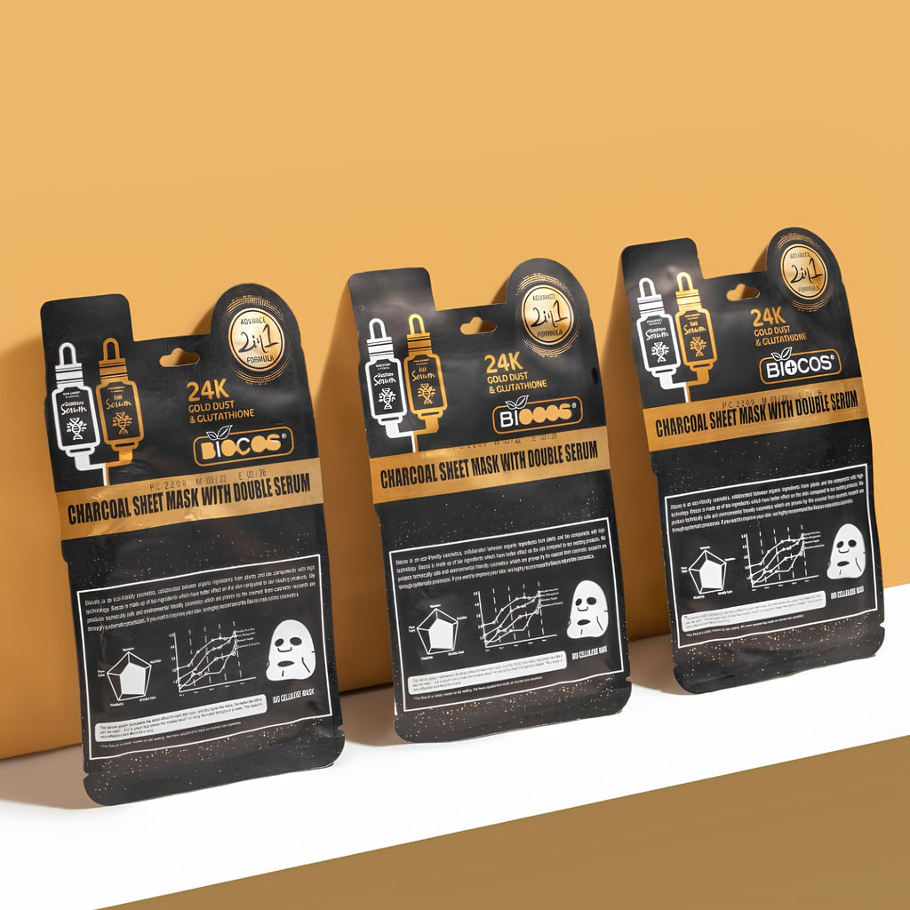 Three Biocos Charcoal Sheet Mask with Double Serum packaging cards arranged side by side on a white surface against a warm tan background.