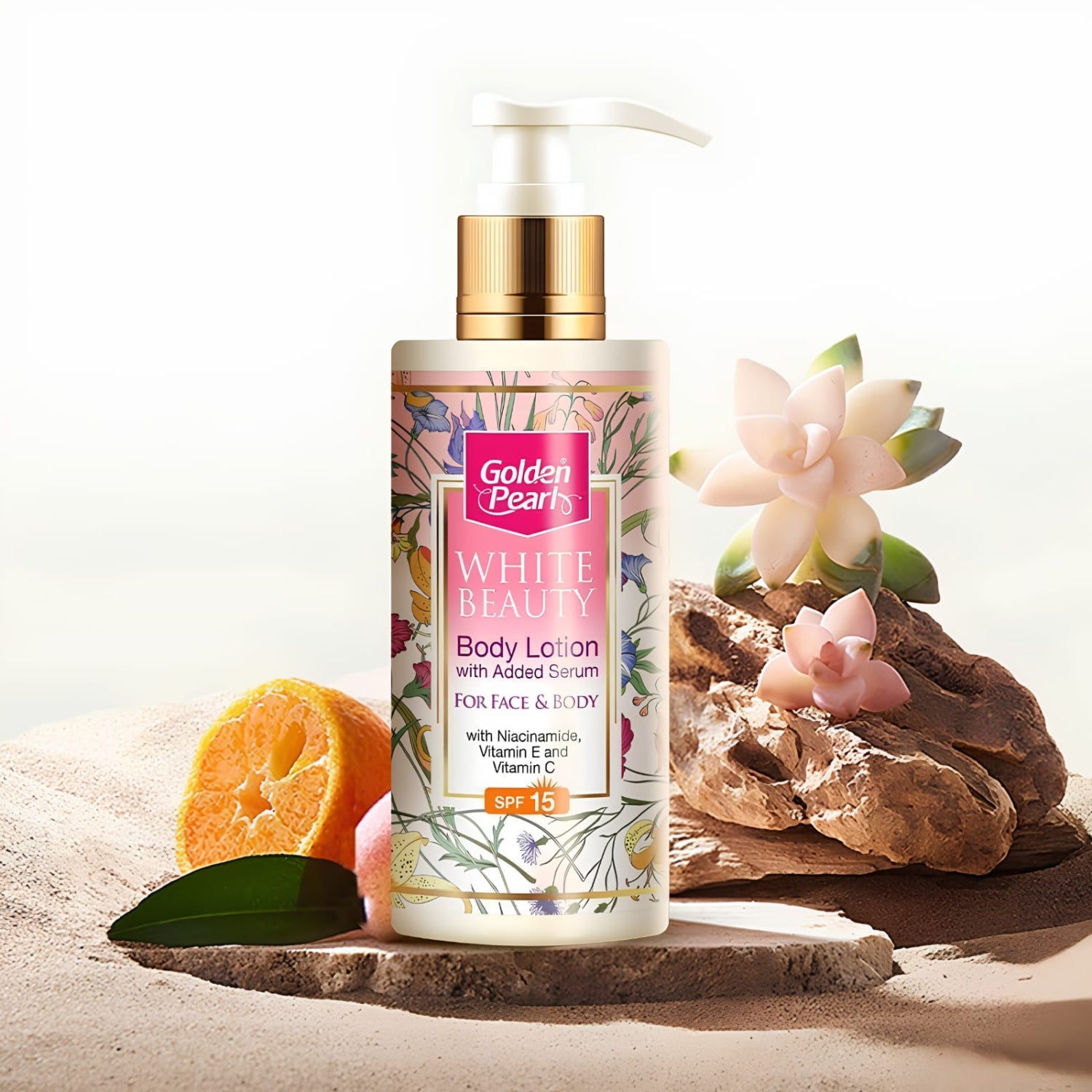 A bottle of Golden Beasts White Beauty Body Lotion with added serum, featuring a gold cap and a pink and floral label, styled on a stone slab with a sliced orange, green leaves, and succulents against a bright white background.
